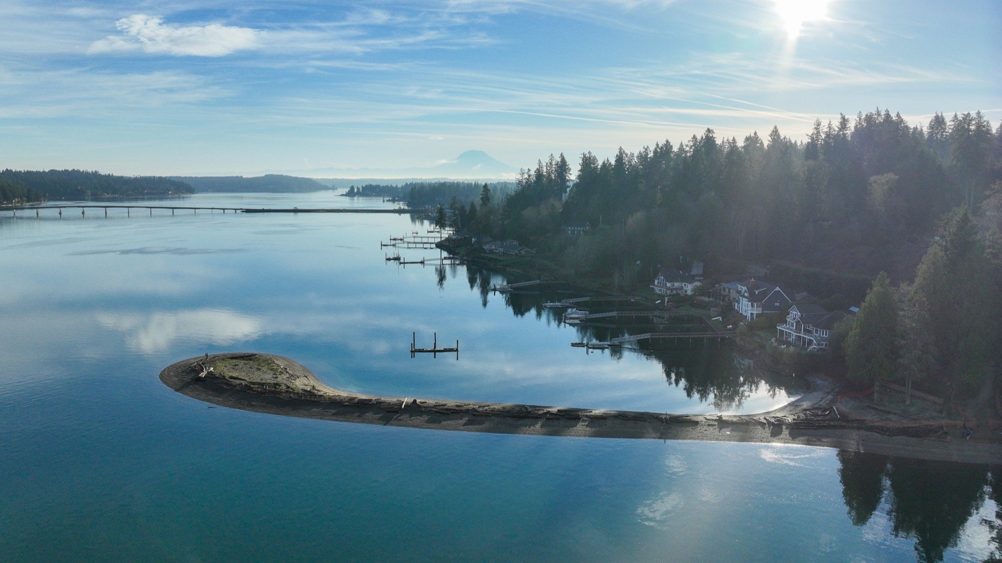 Aerial view of the Gig Harbor peninsula at sunrise, with Puget Sound, evergreen shoreline, and Mount Rainier on the horizon