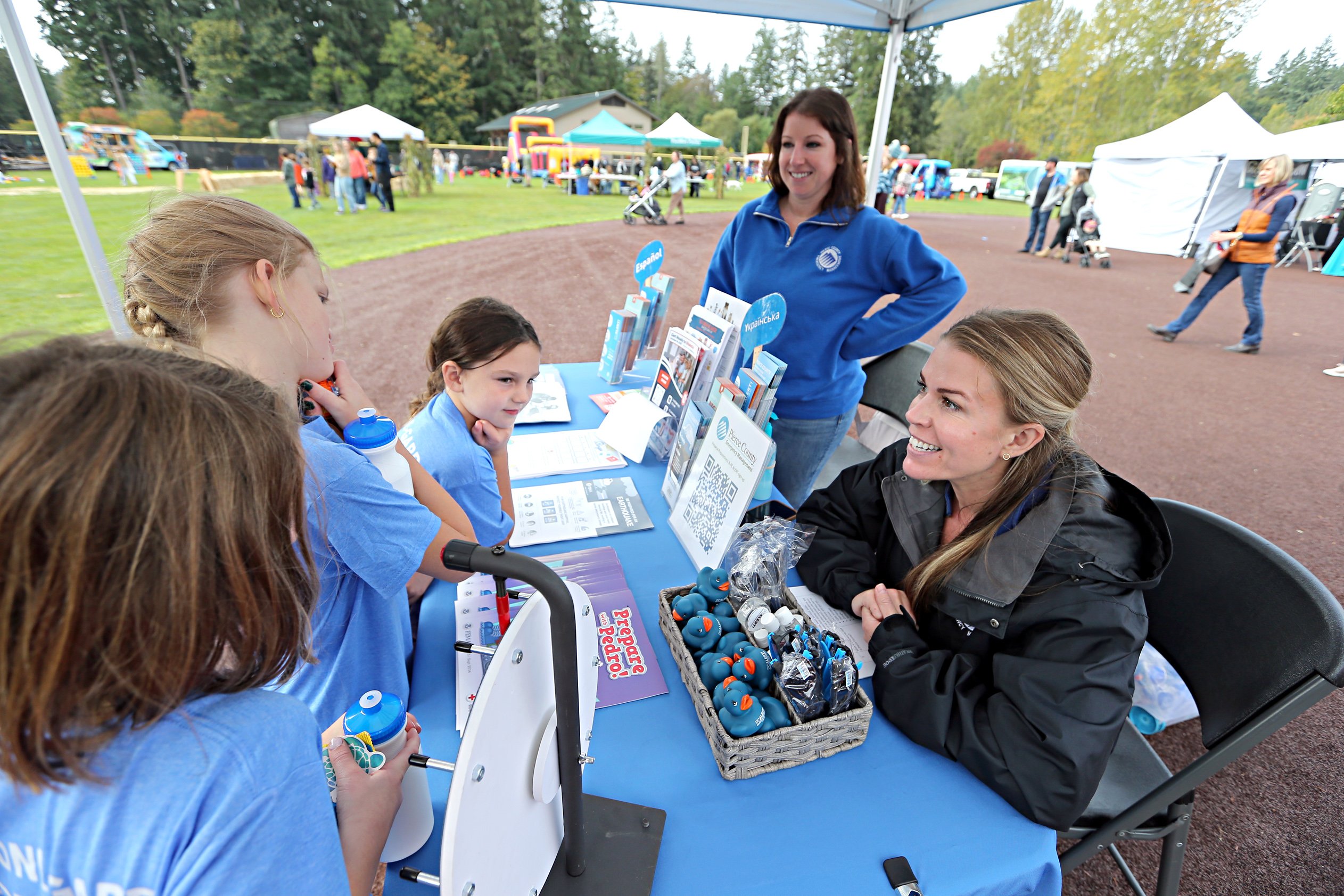 Families gathered at an outdoor community festival booth at a PenMet park